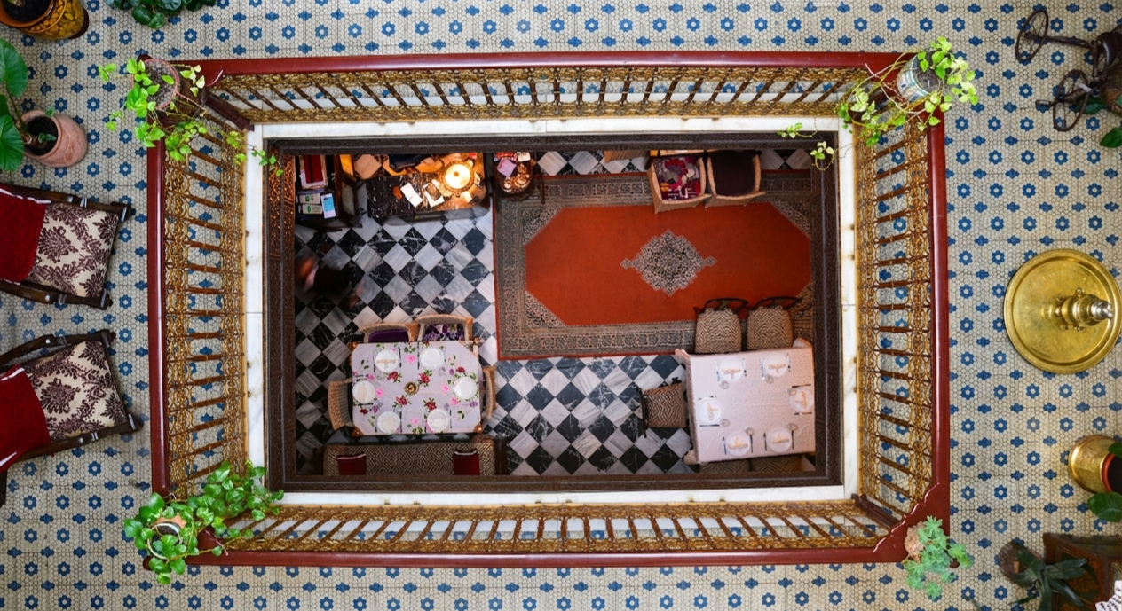 El Reducto — Bird's eye view of the riad courtyard with zellige tiles and traditional Moroccan dining
